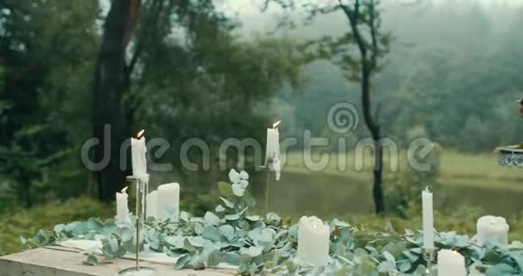 户外桌面装饰着闪电蜡烛树叶鲜花和美味的两层浆果蛋糕4K录像没有视频的预览图