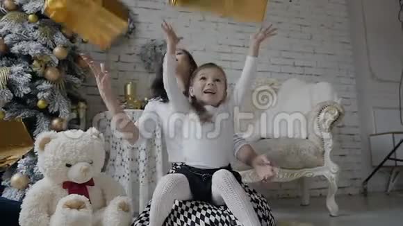一个年轻的女人带着一个小孩坐在一个明亮宽敞的房间里靠近圣诞树的地板上在视频的预览图