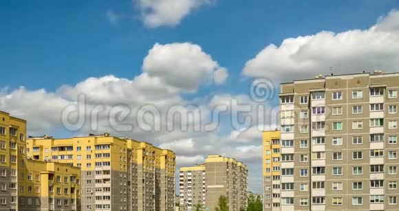 黄色多层公寓楼背景下白色蓬松滚动云的时间流逝片段视频的预览图