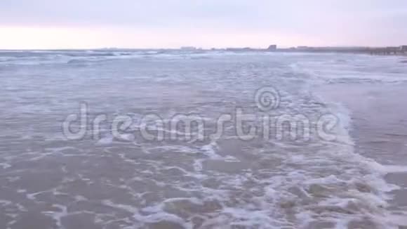 大海里波涛汹涌美丽的海景与沙滩和海岸小镇背景在日落视频的预览图