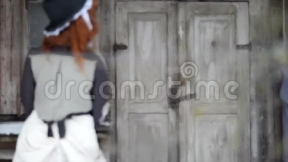 漂亮的红发女孩正站在森林里的老木屋旁边视频的预览图
