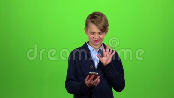 孩子用大拇指指着手机上的照片绿色屏幕慢动作视频的预览图