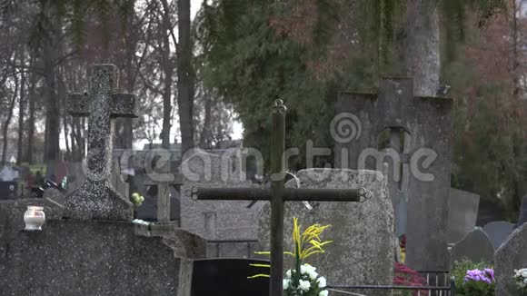 墓石上的蜡烛和十字架的特写和模糊的人4K视频的预览图