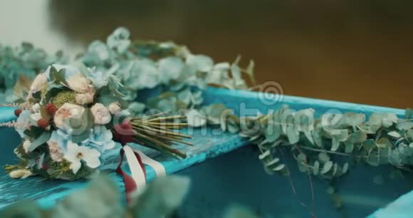 美丽的一束五颜六色的不同的花用红色和白色的丝带包裹在古老的蓝色乡村小船上视频的预览图