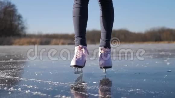 在寒冷的冬日一位年轻女子在结冰的湖面上滑冰户外冬季溜冰场上的溜冰者的腿人视频的预览图