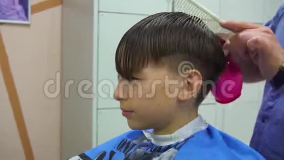 在理发店的男孩可爱的男孩在美发沙龙理发发型用机器剪发视频的预览图