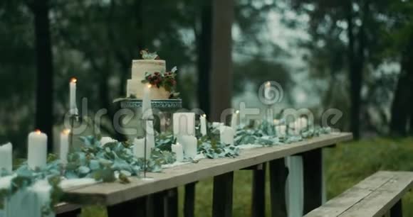 在雾蒙蒙的森林里提供浪漫晚餐的桌子精美的装饰细节树叶花朵蜡烛和双层视频的预览图