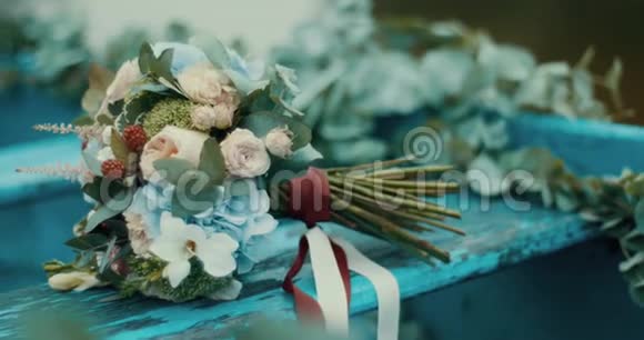 一束美丽的五颜六色的不同花朵在蓝色的乡村背景上用红白丝带包裹4k视频的预览图