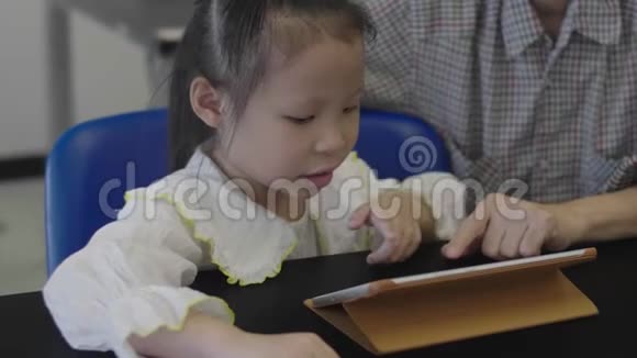 亚洲小女孩和妈妈在图书馆玩数码平板电脑视频的预览图