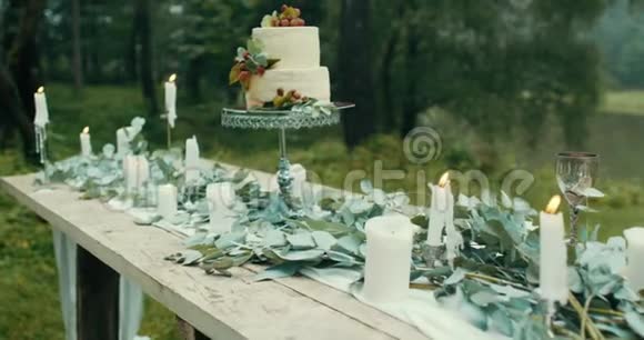 在薄雾森林里浪漫晚餐的可爱装饰桌上摆满了树叶蜡烛鲜花和美味的两层蛋糕视频的预览图