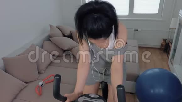 固定自行车上戴耳机的妇女视频的预览图