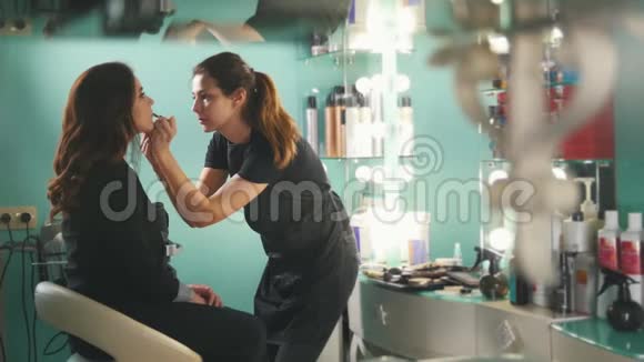 美容店的化妆师为有魅力的女孩化妆发型师做发型特写视频的预览图