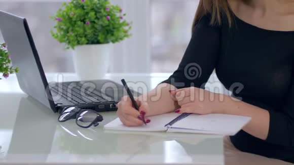 商务人士女孩在笔记本上写作坐在桌子上电脑在室内视频的预览图