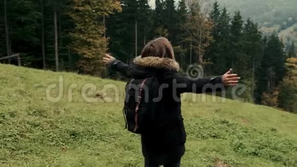 镜头跟随年轻女孩徒步旅行者在山上行走举起手臂飞向空中视频的预览图