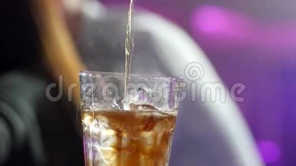 酒吧老板在装有冰块的透明玻璃杯中倒入威士忌或干邑动作缓慢视频的预览图