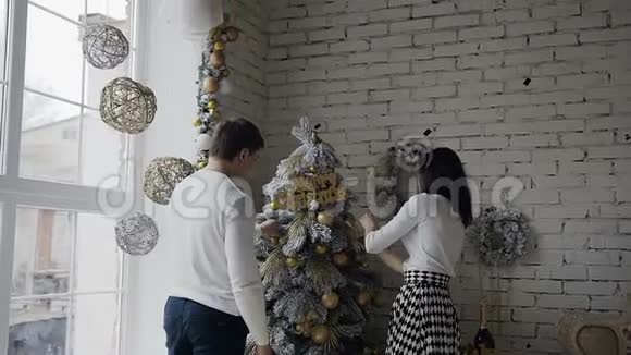 男配女配圣诞树一个幸福的家庭在一棵大圣诞树附近装饰一棵装饰圣诞树视频的预览图