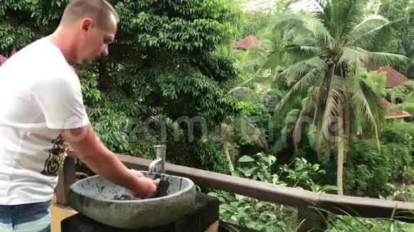 男人在外面用美丽的热带景色洗手洗脸新鲜度和生态理念巴厘岛视频的预览图