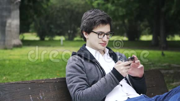 戴眼镜的年轻人在巴伦西亚公园上网视频的预览图