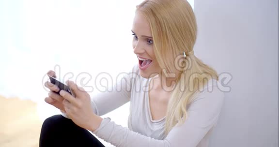兴奋的年轻女子在手机上看短信视频的预览图
