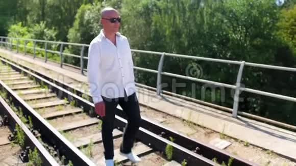 一个秃顶的人在一座废弃的铁路桥上唱歌中弹视频的预览图