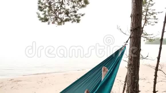 年轻的白种人男性躺在湖边的蓝色吊床上休息视频的预览图