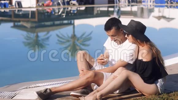 在游泳池附近休息的无忧无虑的恋人度假日光浴放松假期旅游蜜月视频的预览图