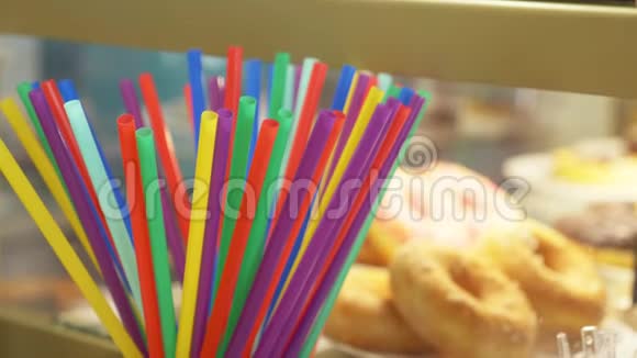 在糖果店橱窗里甜甜圈的背景上用于饮料的彩色吸管4k慢动作视频的预览图