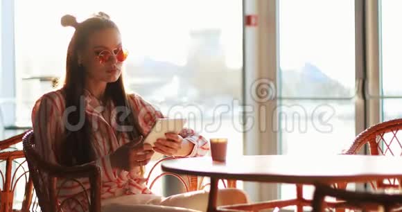 年轻女子在桌子上读到一些东西坐在外面咖啡馆的桌子旁视频的预览图