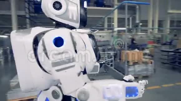 一个白色的机器人在工厂里搬运一件金属物品关闭视频的预览图