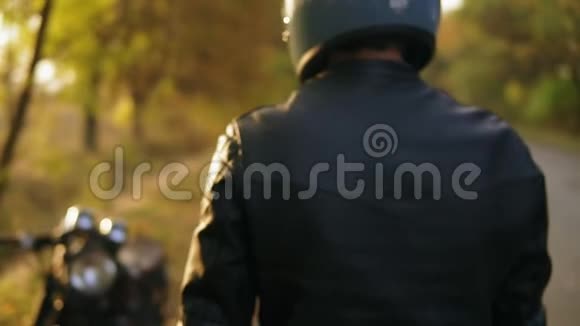 一个戴头盔和皮夹克的人站在自行车前发动引擎视频的预览图