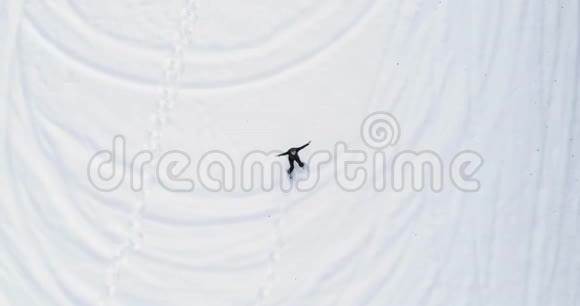 头顶的空中俯视着躺在雪地上的人在冬天穿着雪鞋在白色覆盖着雪的田野上做雪天使人民视频的预览图