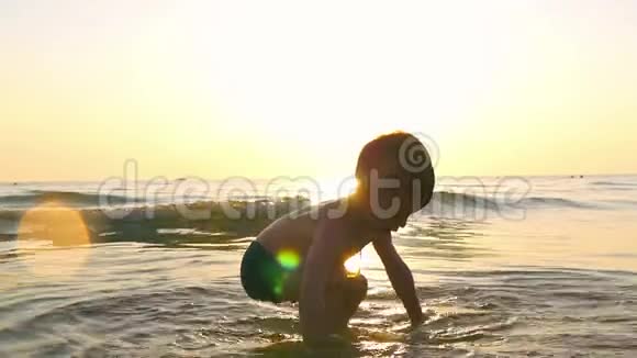 孩子在海边玩水在海浪中在夕阳的背景下视频的预览图