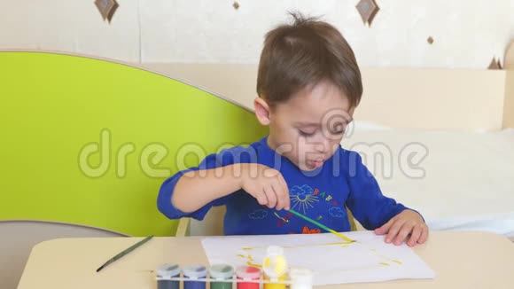 坐在桌子旁的一张白纸上孩子用水彩作画视频的预览图