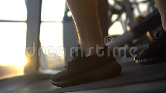 运动员腿在跑步机上行走日落时在健身房晚上锻炼视频的预览图