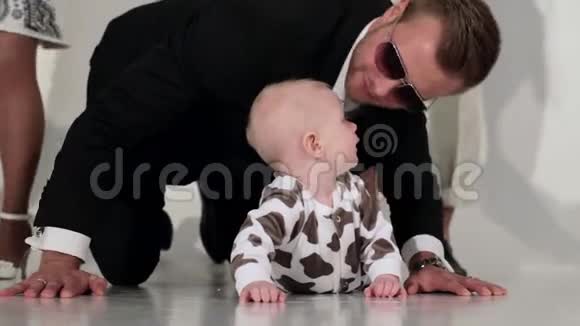 英俊的年轻人在跳舞的背景下和婴儿在地板上玩耍视频的预览图