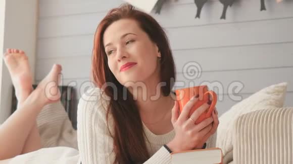 梦幻般的红发女孩在摄影棚里喝着躺在床上的茶视频的预览图