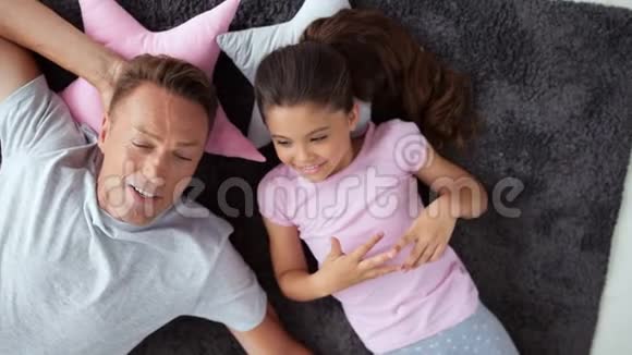 一个快乐的男人和他的小女儿在地板上跳舞的俯视图视频的预览图