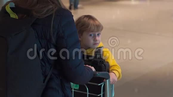 一名女子驾驶她儿子在机场的行李车上慢镜头视频的预览图