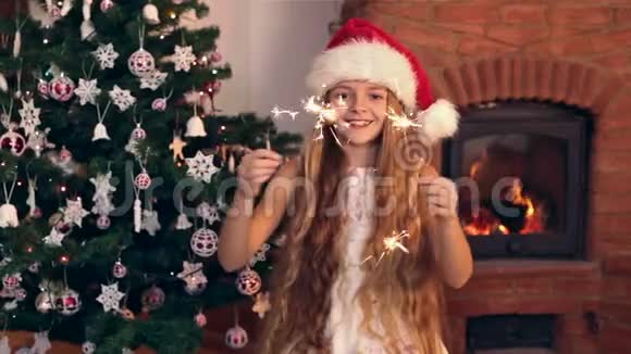 戴着圣诞帽的快乐女孩笑着挥舞着圣诞火花视频的预览图