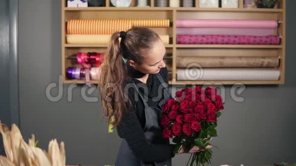 来自专业花店的完美红玫瑰花束年轻迷人的女性花店布置美丽的花束视频的预览图