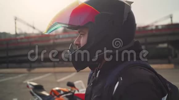 街上日落时分一个戴黑色头盔的摩托车手的肖像彩色面罩视频的预览图