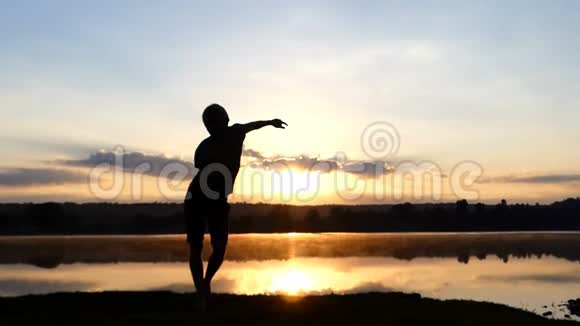 欢乐的人在夕阳西下的湖岸自由跳舞视频的预览图