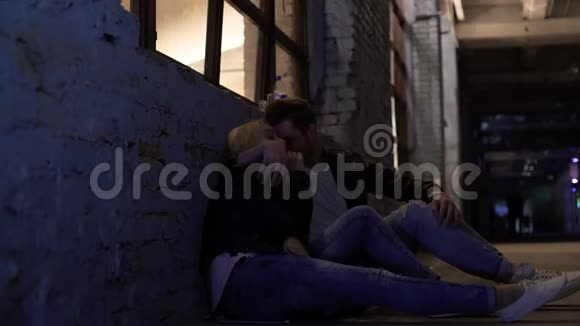 疲惫的女性和男性坐在靠近墙壁的地方聊天在夜总会聚会后视频的预览图