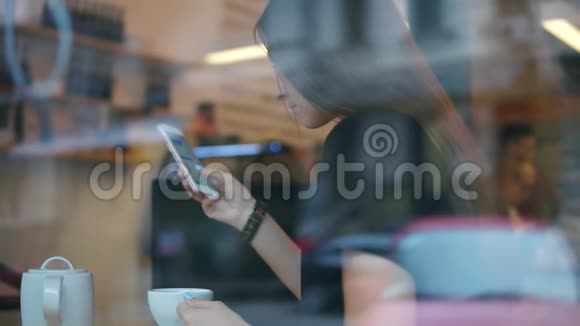 从街道上看到一位年轻女士她用手机发长发短信喝着茶或咖啡视频的预览图