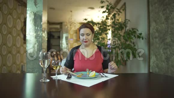漂亮的中年黑发女人穿着红裙子一个人用筷子吃饭在高档餐厅吃饭视频的预览图