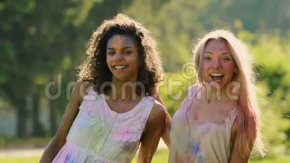 美丽的女性朋友用五颜六色的颜料拥抱微笑着对着镜头视频的预览图