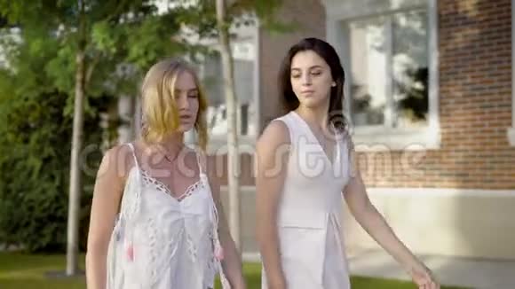 两个穿着白色夏装的年轻女孩走在街上梦幻般地望着远方视频的预览图