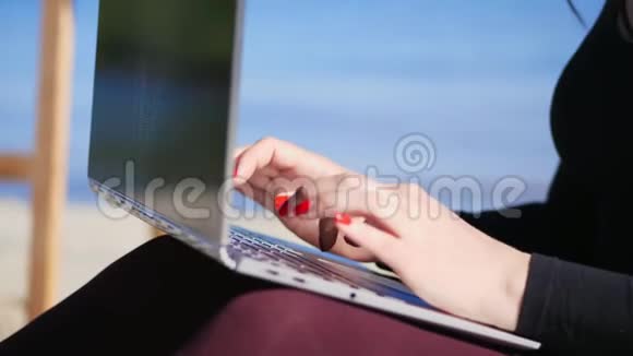 夏天海边特写女性手与鲜红的指甲键入笔记本电脑键盘在笔记本电脑上工作视频的预览图