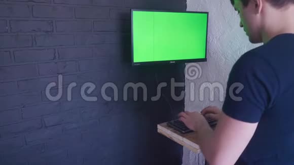 年轻人正在用一个绿色屏幕模拟电脑工作4K在键盘上慢慢打字视频的预览图