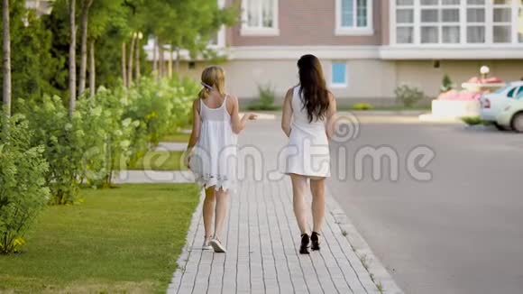 两个穿白色衣服的时髦女人在人行道上散步和交谈视频的预览图